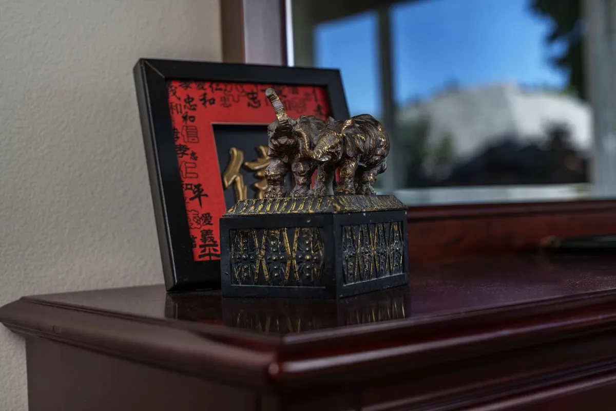 A thoughtfully decorated living area showcasing an elephant figurine, a decorative box, and framed art—accentuated by guests engaging in quiet conversation and admiring the decor.
