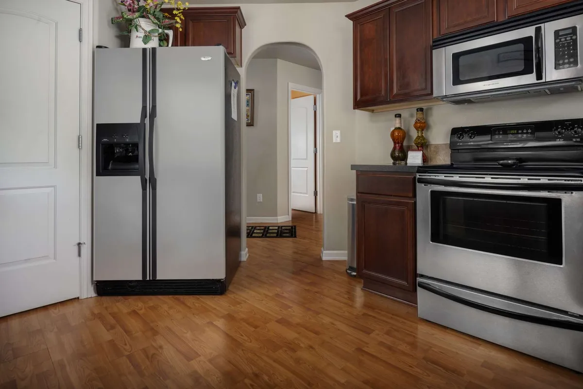 A close-up of the kitchen’s stainless steel refrigerator, modern oven, and microwave with wooden cabinetry, highlighting the high-end appliances and functional design for meal preparation and entertaining.