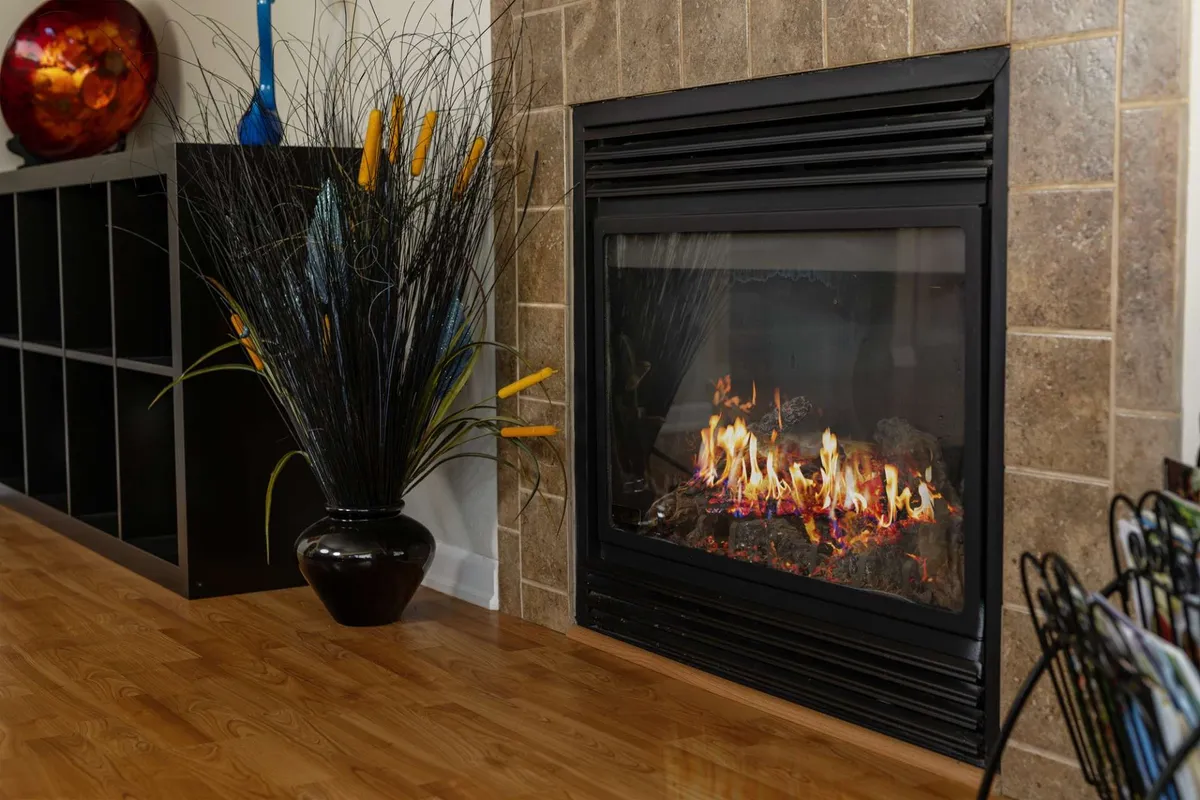 This interior image centers on a cozy fireplace with a decorative vase on the mantle and a warm wooden floor. The inviting setup suggests a space where families gather to relax and enjoy each other's company, especially during cooler seasons.